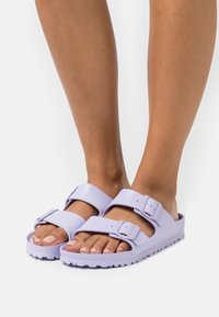 Purple rubber sandals with two adjustable straps and buckles. Textured sole and smooth upper surface. Casual slip-on design.