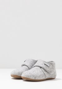 Szare filcowe kapcie z okrągłym noskiem, z zapięciem na rzep i gumową podeszwą dla lepszej przyczepności. Miękka faktura i prosty design.