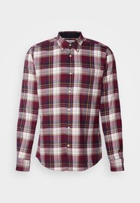 Chemise à manches longues boutonnée avec un motif à carreaux bordeaux, blanc, gris et jaune et une poche poitrine sur fond blanc.