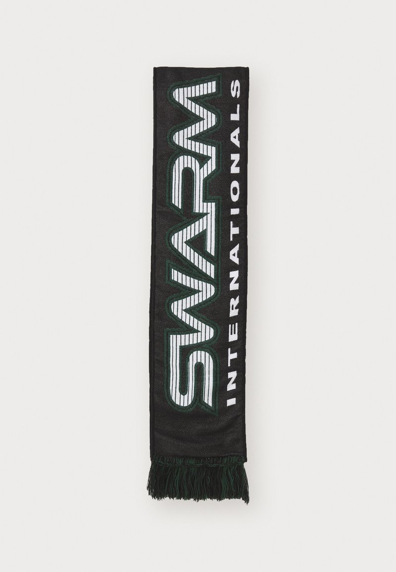 Cachecol preto com texto tecido em verde e branco dizendo "SWARM" e "INTERNATIONALS", apresentando extremidades com franjas. Forma retangular, textura suave.