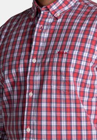 Rood en blauwe geruite shirt met een button-down kraag, witte knopen en een borstzak met geborduurd logo-detail.