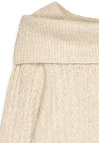 Maglione di colore crema in maglia, con un ampio colletto ripiegato caratterizzato da un motivo a trecce e una finitura morbida e testurizzata.