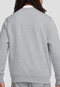 Gray sweatshirt made of soft fabric. Features a crew neck, ribbed cuffs, and hem. Plain back with no patterns or visible hardware.