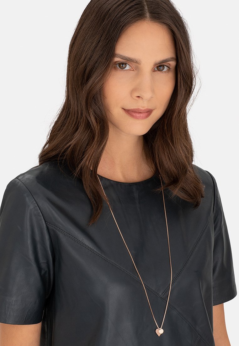 Zwart leren top met korte mouwen, een gladde textuur en diagonale naaddetails, gecombineerd met een roségouden ketting met een hartje.