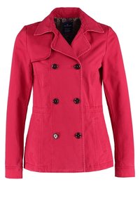 Chaqueta roja de doble botonadura hecha de algodón con cuello puntiagudo. Presenta grandes botones negros, bolsillos laterales y un forro texturizado.