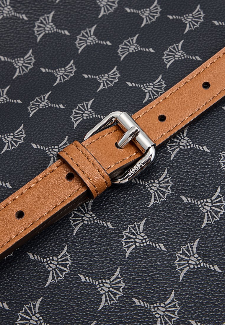 Hellbraunes Lederarmband mit einer silbernen Schnalle auf einem strukturierten schwarzen Hintergrund, der ein wiederholendes hellgraues florales Muster aufweist.