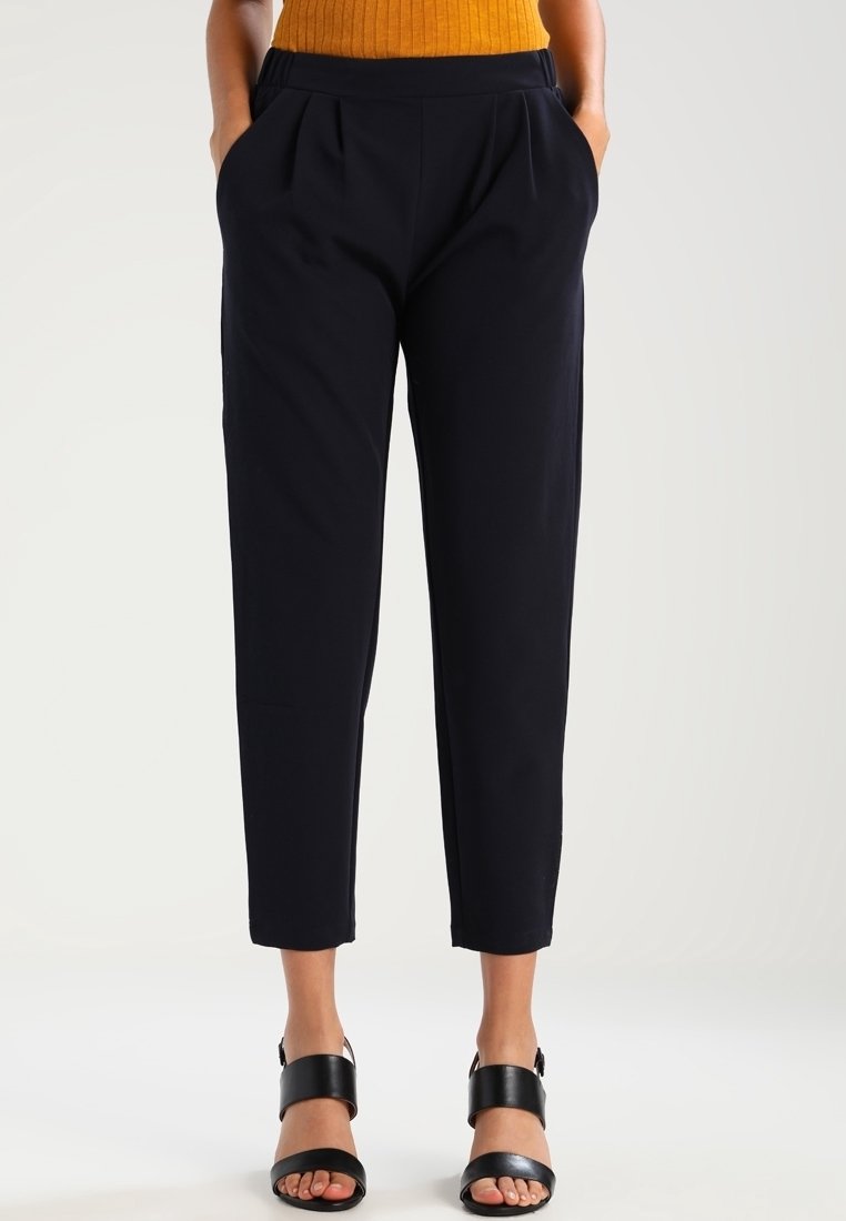 Pantaloni sartoriali blu navy con una vestibilità rilassata, frontale plissettato e cintura elastica, caratterizzati da una texture liscia e una lunghezza cropped.