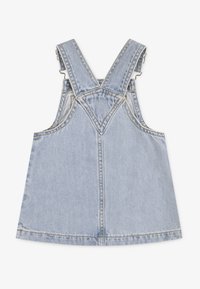 Φόρεμα ολόσωμο τζιν σε ανοιχτό μπλε χρώμα, με ρυθμιζόμενους ιμάντες που σταυρώνουν στην πλάτη, τσέπες και ορατές ραφές στο τελείωμα και στις ραφές.