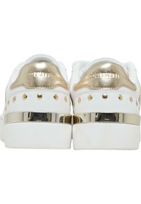 Baskets blanches avec des accents dorés métalliques, comportant des détails cloutés et une bande dorée brillante sur le talon. Matériau doux et forme arrondie.