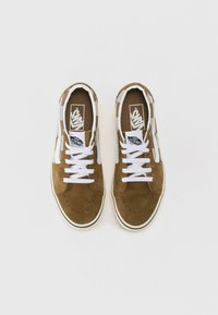 Smeđi nubuk tenesici s bijelim vezicama, klasičnog dizajna, s kontrastnim bijelim bočnim prugama i Vans logotipom na jeziku.