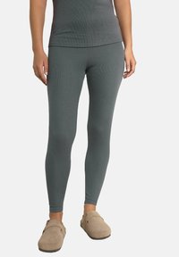 Grå ribbade leggings gjorda av stretchigt tyg, med en åtsittande design. Bärs med ljusbruna träskor.
