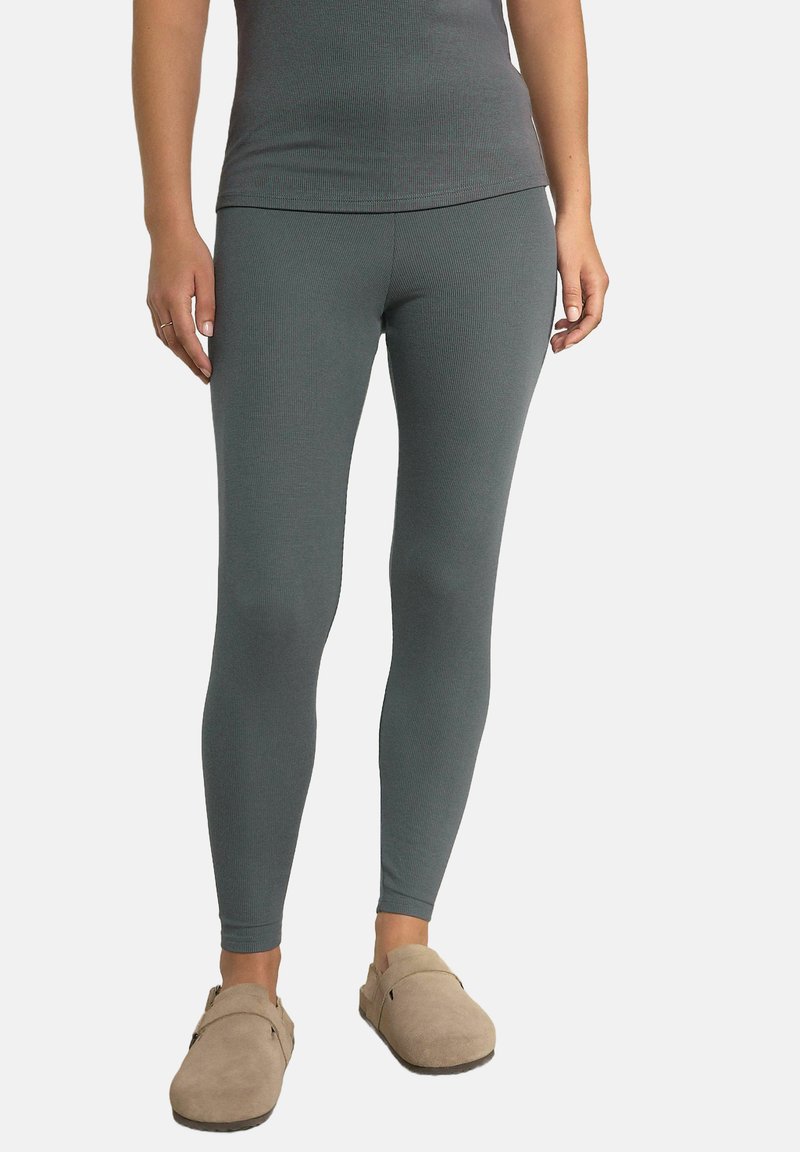 Grå ribbade leggings gjorda av stretchigt tyg, med en åtsittande design. Bärs med ljusbruna träskor.