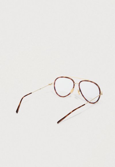 Aviatorke očala v zlatem okvirju s kornjačevimi obrobami in prozornimi lečami, ki ležijo na belem površju.