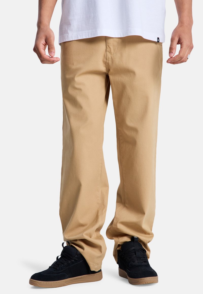 Pantaloni chino beige in cotone con vestibilità comoda e gamba dritta. Abbinati a sneakers nere con dettagli in suede e suola in gomma.