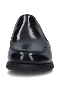 Mocassini in vernice nera con una finitura liscia e lucida, punta arrotondata e dettagli di cucitura discreti nelle cuciture. Suola in gomma nera bassa.