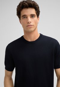 Dunkelblaues, kurzärmliges Strick-T-Shirt mit Rundhalsausschnitt, glatter Textur und dezent geripptem Halsabschluss. Gerade Passform, lässiges Design.