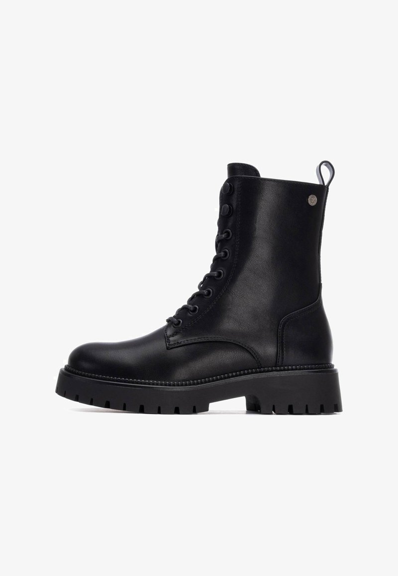 Botas de cuero negras hasta el tobillo con punta redonda, cordones en la parte frontal y suela de goma resistente. Cuenta con una lengüeta lateral y detalles decorativos.