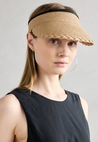 Sombrero de ala ancha de paja trenzada en beige con una banda de cinta negra, que presenta un borde ondulado y un diseño estructurado y curvado.
