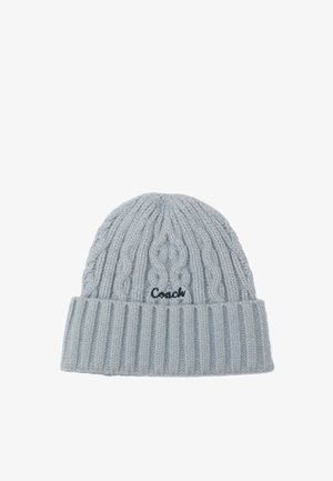 Gorro de punto gris con patrón de trenzas y puño acanalado. Presenta un logo bordado de "Coach" en hilo oscuro en la parte frontal.