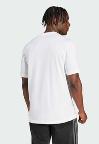 Hvid bomulds t-shirt med korte ærmer, rund halsudskæring og en afslappet pasform, vist fra ryggen. Har minimale sømme og en glat tekstur.