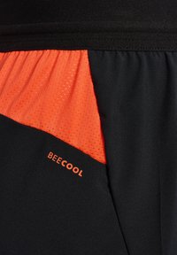Zwarte sportshorts met een gestructureerd oranje paneel, waarop de merknaam "BECOOL" in oranje is gedrukt aan de onderrand.