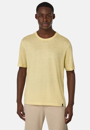 Camiseta amarilla de manga corta con cuello redondo, corte relajado y una textura ligera. Presenta una pequeña etiqueta negra con el logotipo en el dobladillo.