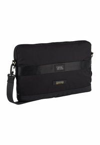 Sort nylon laptop taske med en glat tekstur, slankt design og justerbar rem. Har et logo patch og mærke detaljer på forsiden.