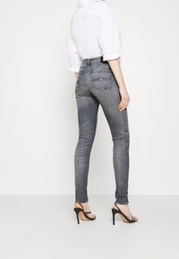 Vaqueros ajustados en denim gris oscuro, con una cintura de altura media, cinco bolsillos y un ligero desvanecimiento. Combínalos con tacones de aguja negros.