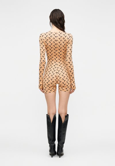 Εφαρμοστό ολόσωμο κορμάκι με μακριά μανίκια σε ροδακινί χρώμα με μαύρο μοτίβο σε σχήμα σεληνοειδούς φάσης. Διαθέτει μήκος σορτς και απαλή, λεία υφή. Συνδυασμένο με μαύρες μπότες έως το γόνατο.