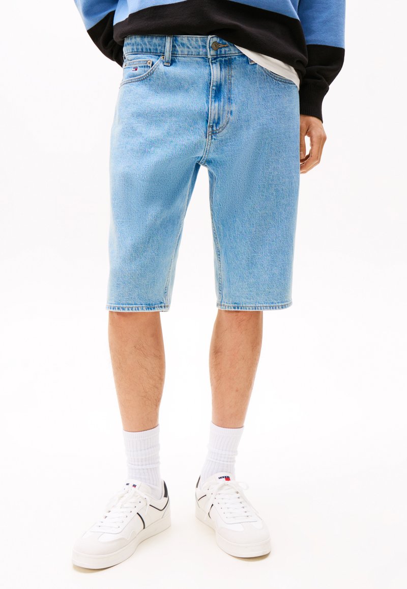 Lyse blå denimshorts med avslappet passform, oppbrettede kanter og frontlommer. Båret med hvite sneakers og ribbede hvite sokker.