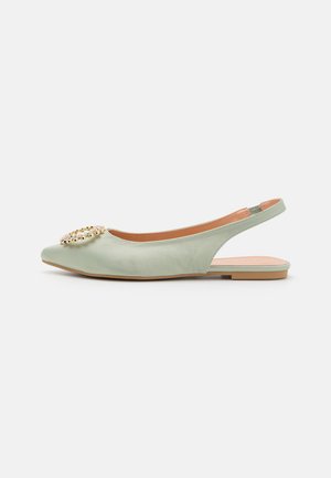 Chaussure slingback plate vert clair pointue avec boucle décorative en or et cristal sur le dessus et semelle beige.