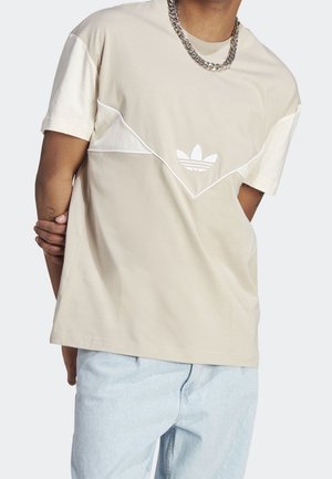 Beige Baumwoll-T-Shirt mit weißen Akzenten. Verfügt über ein großes dreieckiges Design und ein gesticktes Logo auf der Brust. Kurze Ärmel und lockere Passform.