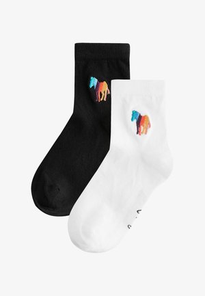 Mustvalged pahkluukad, kummalgi on külje peal väike mitmevärvilise hobuse tikandiga logo.