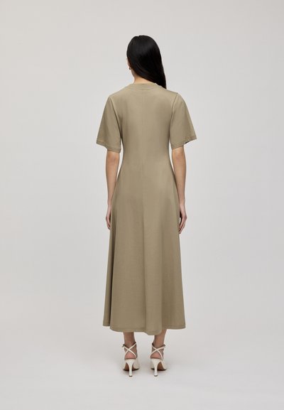 Khaki midi sukienka o luźnym kroju, z krótkimi rękawami, okrągłym dekoltem i gładkim materiałem, połączona z jasnymi sandałami na obcasie.