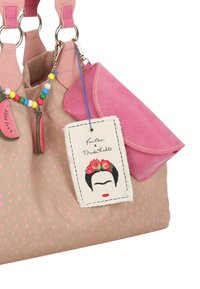Borsa in canvas con accenti rosa, texture a pois e un'etichetta con un'illustrazione di Frida Kahlo. Presenta due spallacci e numerosi dettagli.