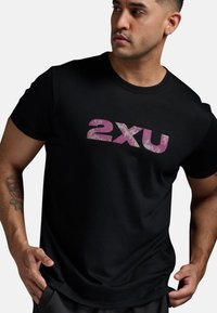 Svart kortärmad t-shirt i bomull med en stor rosa "2xu" logotyp över bröstet med en texturerad yta.