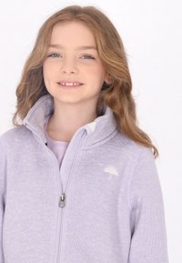 Chaqueta de color lila con cremallera, hecha de material suave, con cuello alto, un pequeño logo de paraguas y detalles de tejido texturizado.