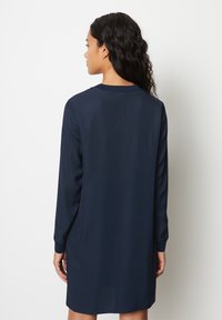 Marineblaue Langarmkleid mit geradem Schnitt, glatter Textur und einfachem Kragen, mit einer zentralen Naht auf der Rückseite.