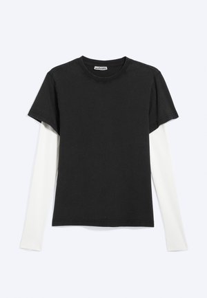 Black short-sleeve T-shirt layered over a white long-sleeve shirt, flat lay on light gray background with WEEKDAY label visible inside collar.