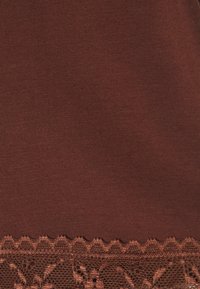 Hnědá látka s ribbovanou texturou, zdobená krajkovým lemem s květinovým vzorem a vlnitým okrajem. Měkký a jemný detail na spodní části.