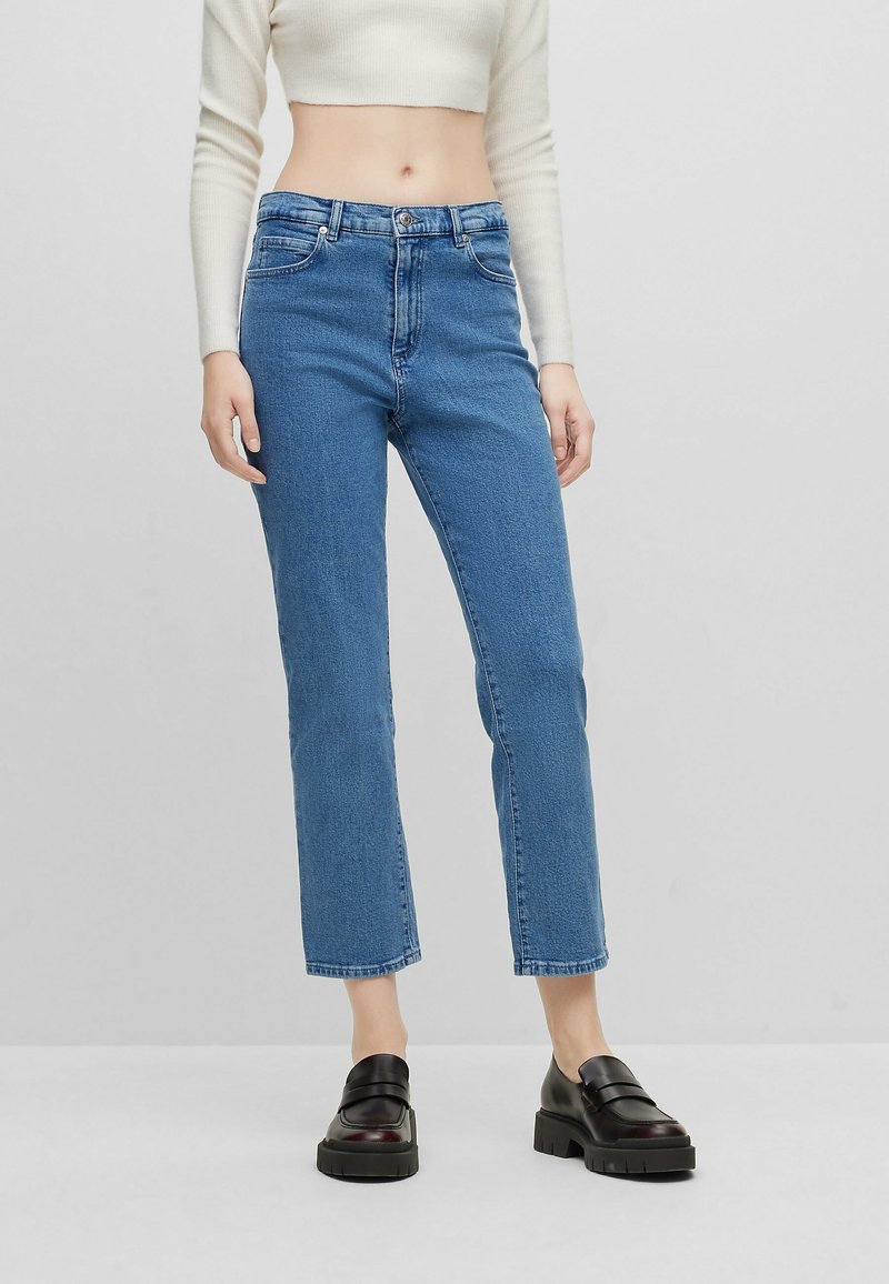 Blå denimjeans med rak benpassform, medelhög midja och fem-fickorsdesign. Tyget har en subtil textur med en klassisk finish.