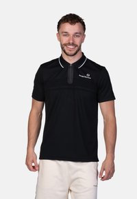 Polo shirt nera con maniche corte, caratterizzata da un colletto con mezza zip, dettagli bianchi sul colletto e un logo sul petto. Tessuto dalla consistenza liscia.