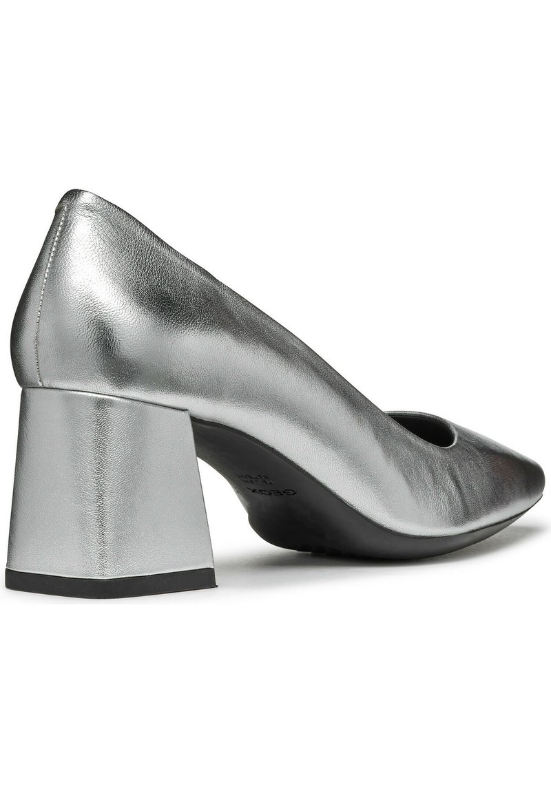 Silberne Leder-Pumps mit hohen Absätzen, klobigem Absatz, abgerundetem Zehenbereich und Aussparung an der Vorderseite. Glatte, metallische Oberfläche ohne Muster.