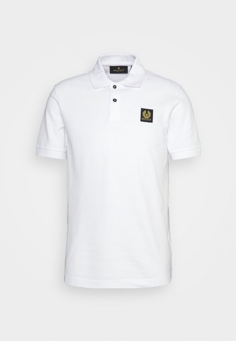 Hvit polo-skjorte laget av bomull, med klassisk krage, tre svarte knapper og en svart firkantet lapp med logo på brystet.