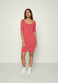 Vestido com estampado floral vermelho, com decote redondo, mangas curtas e três botões decorativos na frente. Usado com ténis brancos.