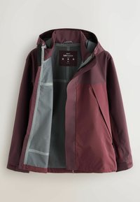 Uopnet bordeaux vandtæt jakke med hætte, grå indvendig foring og label med teksten "Next DryTech M" synlig indeni.