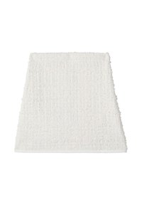 Un tappetino per bagno bianco spesso e texturizzato con materiale simile al cotone; forma rettangolare con bordi frangiati e superficie morbida.