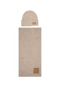 Beanie in maglia beige con risvolto e etichetta in pelle, abbinato a una sciarpa rettangolare coordinata con una texture e un'etichetta simili.