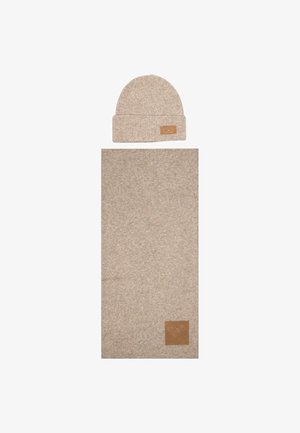 Beige knit beanie with a folded cuff and leather tag, paired with a matching rectangular scarf featuring a similar texture and tag.