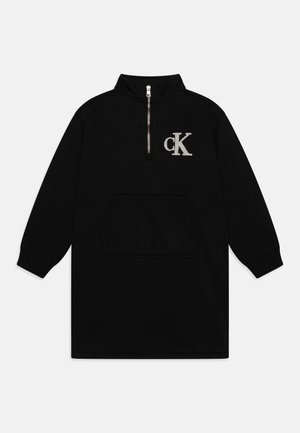 Abito pullover lungo nero a maniche lunghe con colletto alto, chiusura con zip a metà, tasca frontale e logo "cK" ricamato in argento sul petto.